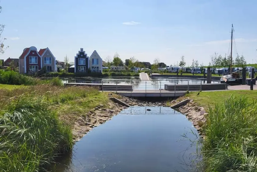 Ein kleiner Fluss mit grünen Ufern führt zu den Ferienhäusern
