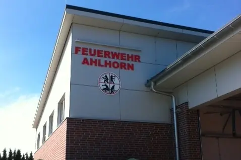 SItzbänke mit Sonnenschirmen vor dem Feuerwehrgebäude mit Schriftzug