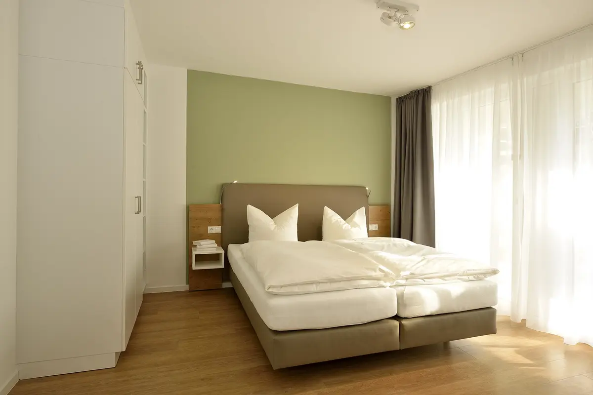 Ein Doppelbett im hell eingerichteten Schlafzimmer