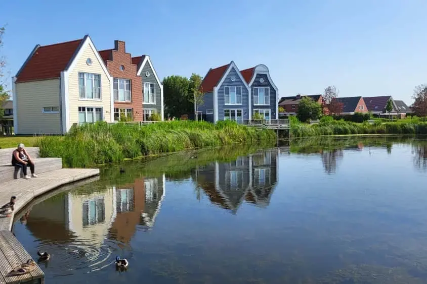 Ferienhäuser am grünen Ufer mit einer Steintreppe zum Wasser