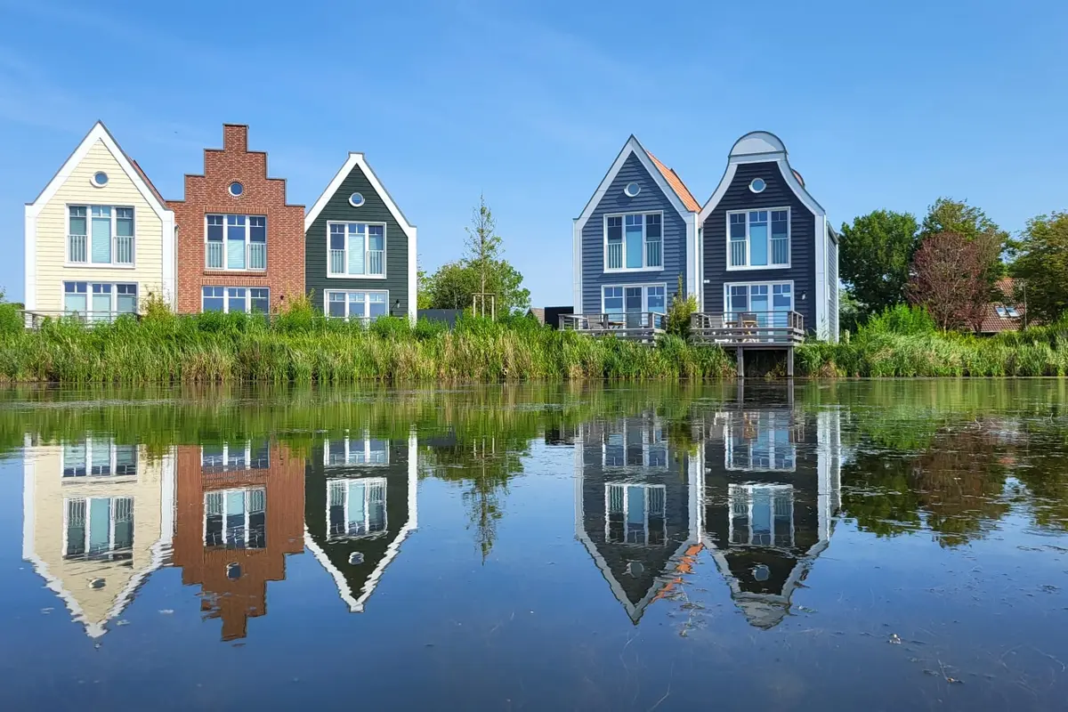 Ferienhäuser umgebenvon dichtem Grün spiegeln sich im Wasser